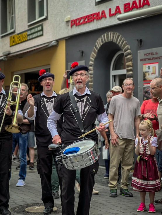 a man holding a congregating band in his hands and another man with a red hat on with two trumpets and a trumpet