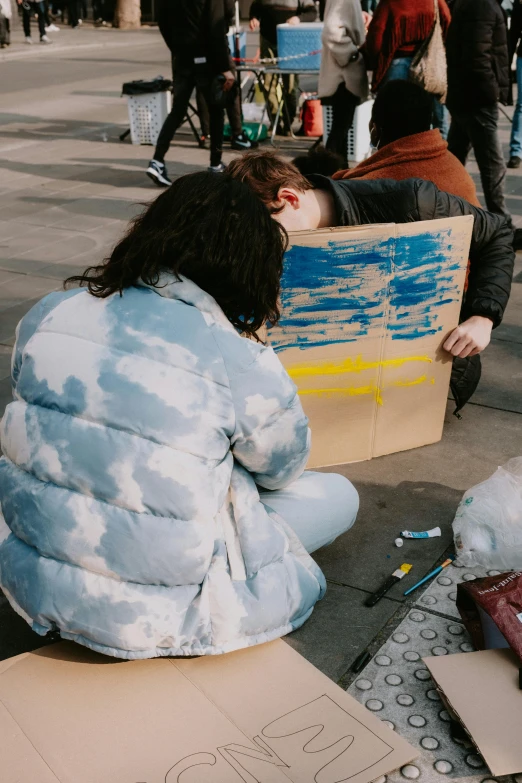 woman sitting on the ground on her knees holding a cardboard box