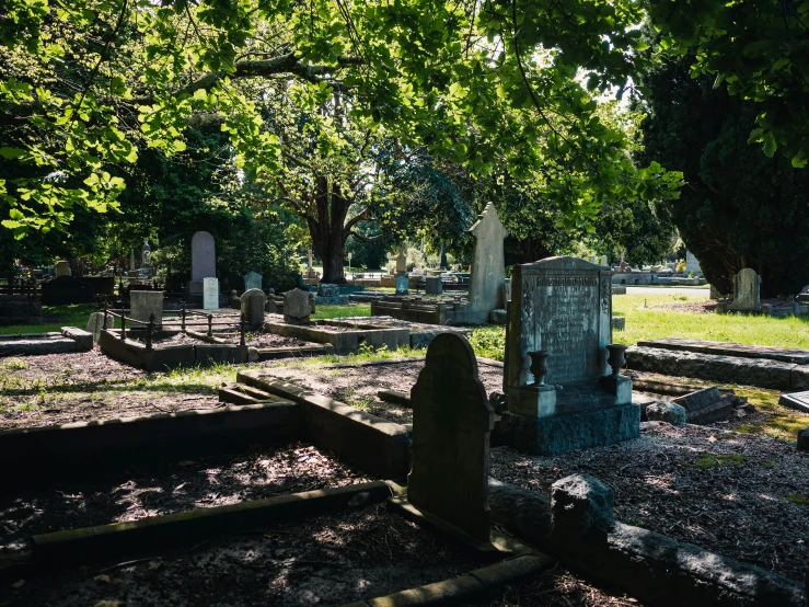 several headstones sit in the grass on a cemetery grounds