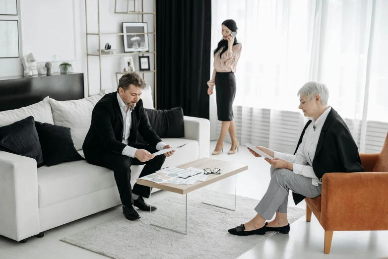 a couple of men sitting in a living room near a woman standing