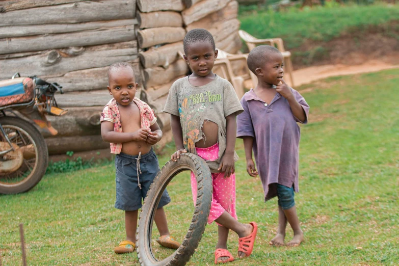 three children are standing outside with tires