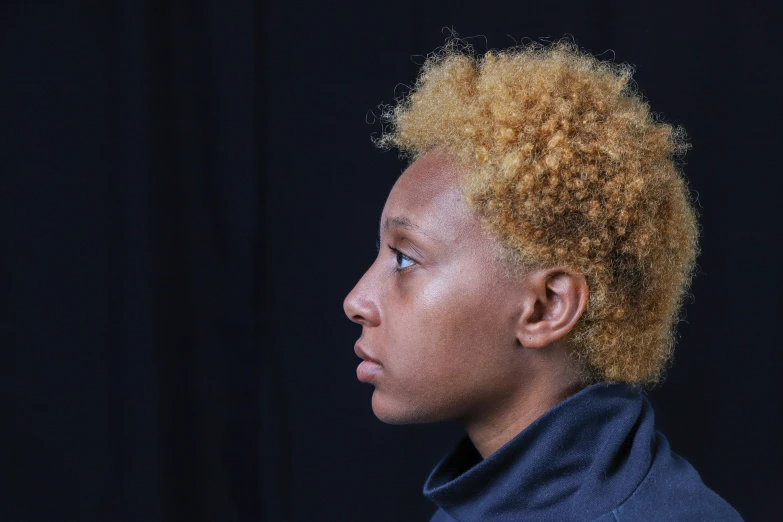 a black woman with short curly hair looks off into the distance