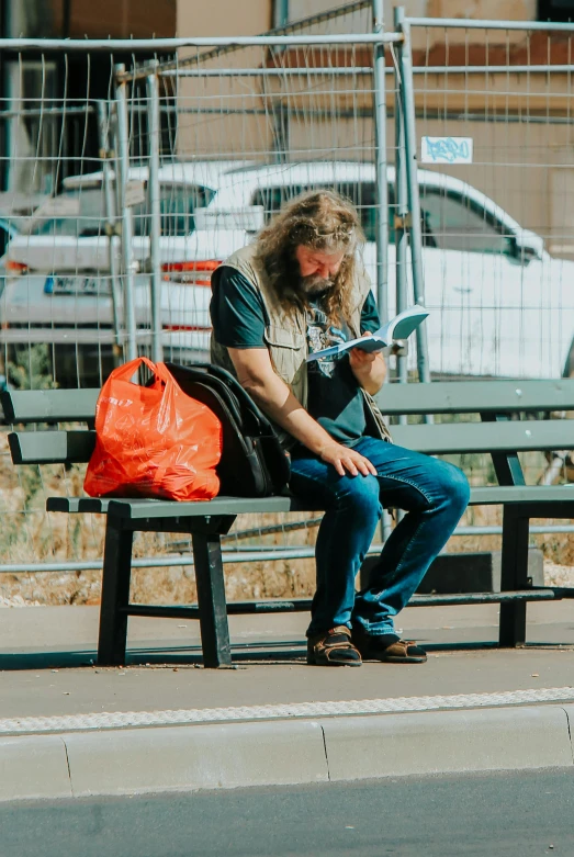 a young man sitting on a bench using his electronic device