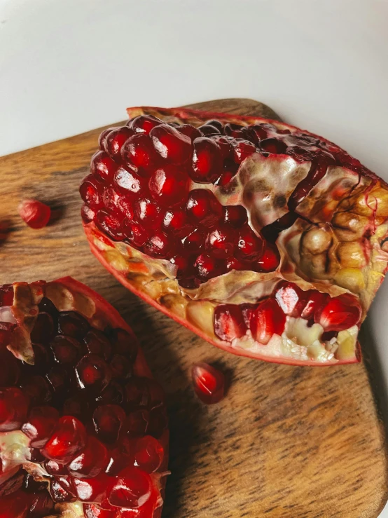 two halves of pomegranate that are laying on a board