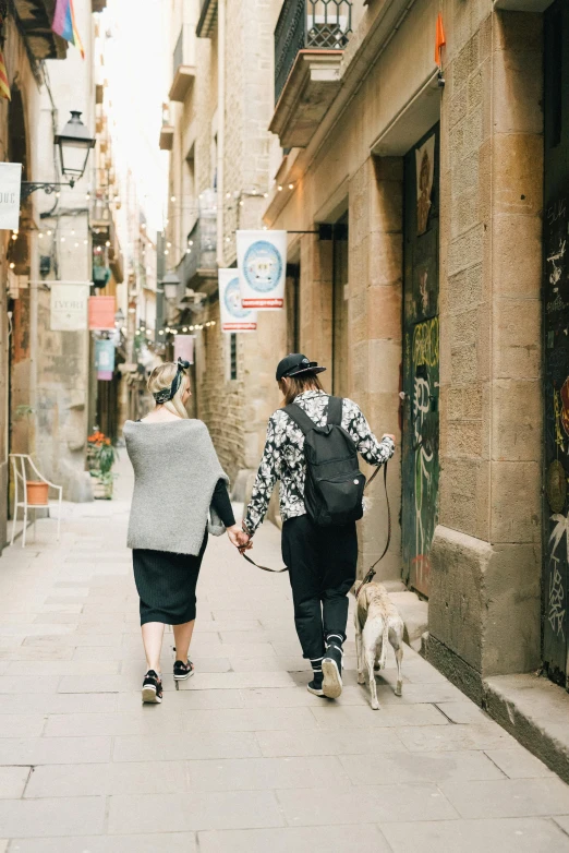 two women walking a dog down a street