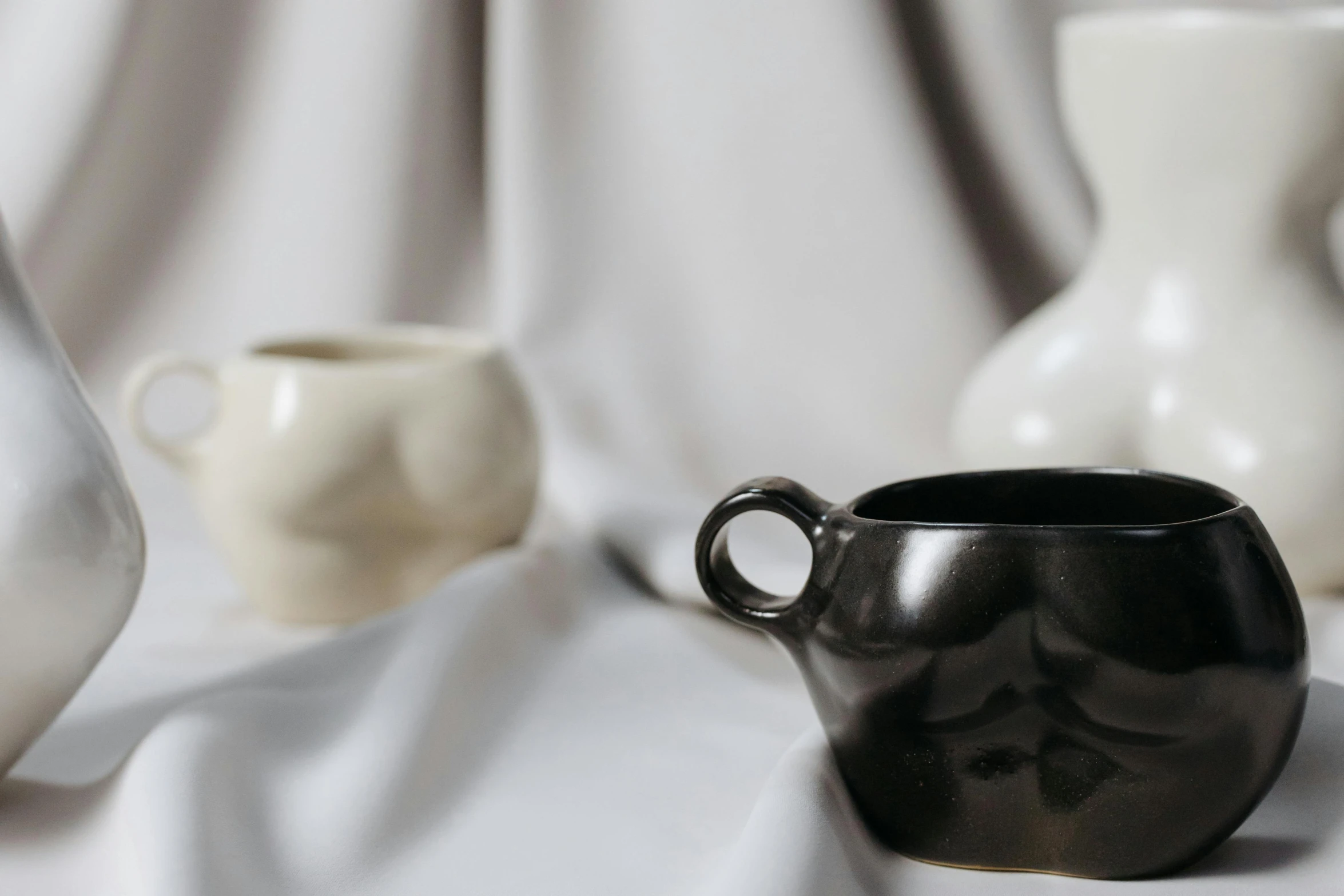 three ceramic vases placed side by side on white fabric