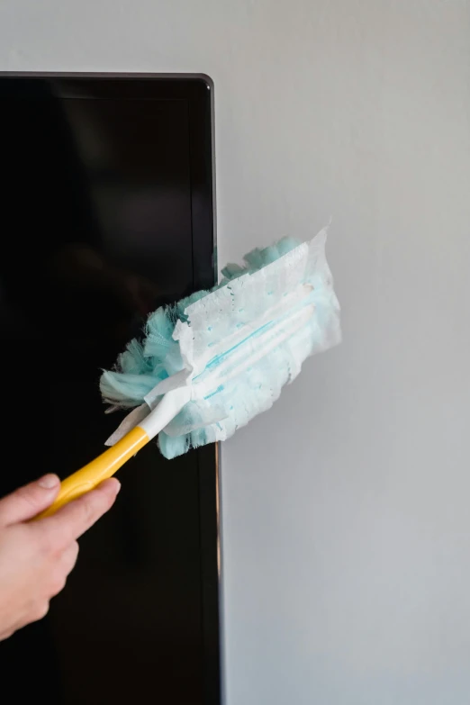 a hand that is holding a toothbrush to paint a wall