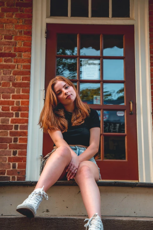 a woman wearing high - tops sits on a step by the door