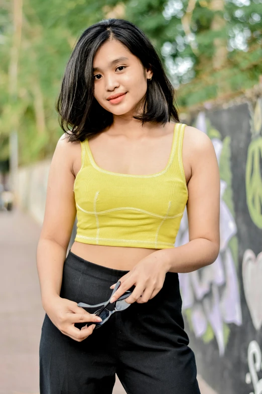 a  posing with her skateboard in front of graffiti