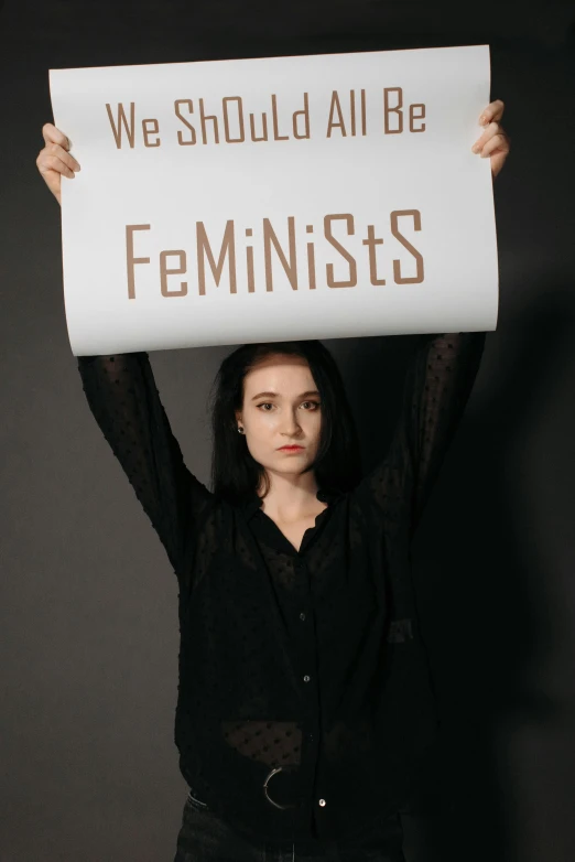 a woman holding up a sign with an image of feminists on it