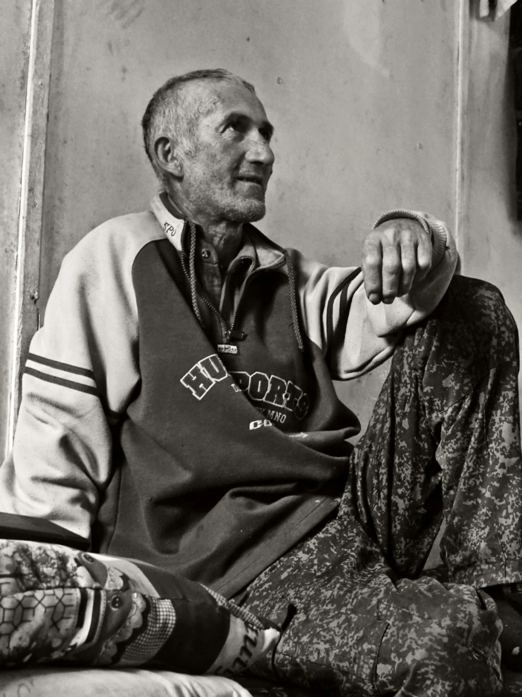 an older man wearing a hoodie sitting on the floor