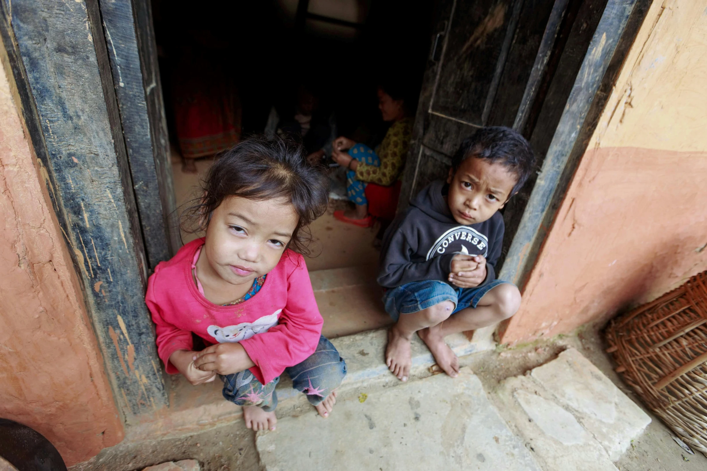 two little s sitting on steps looking in window