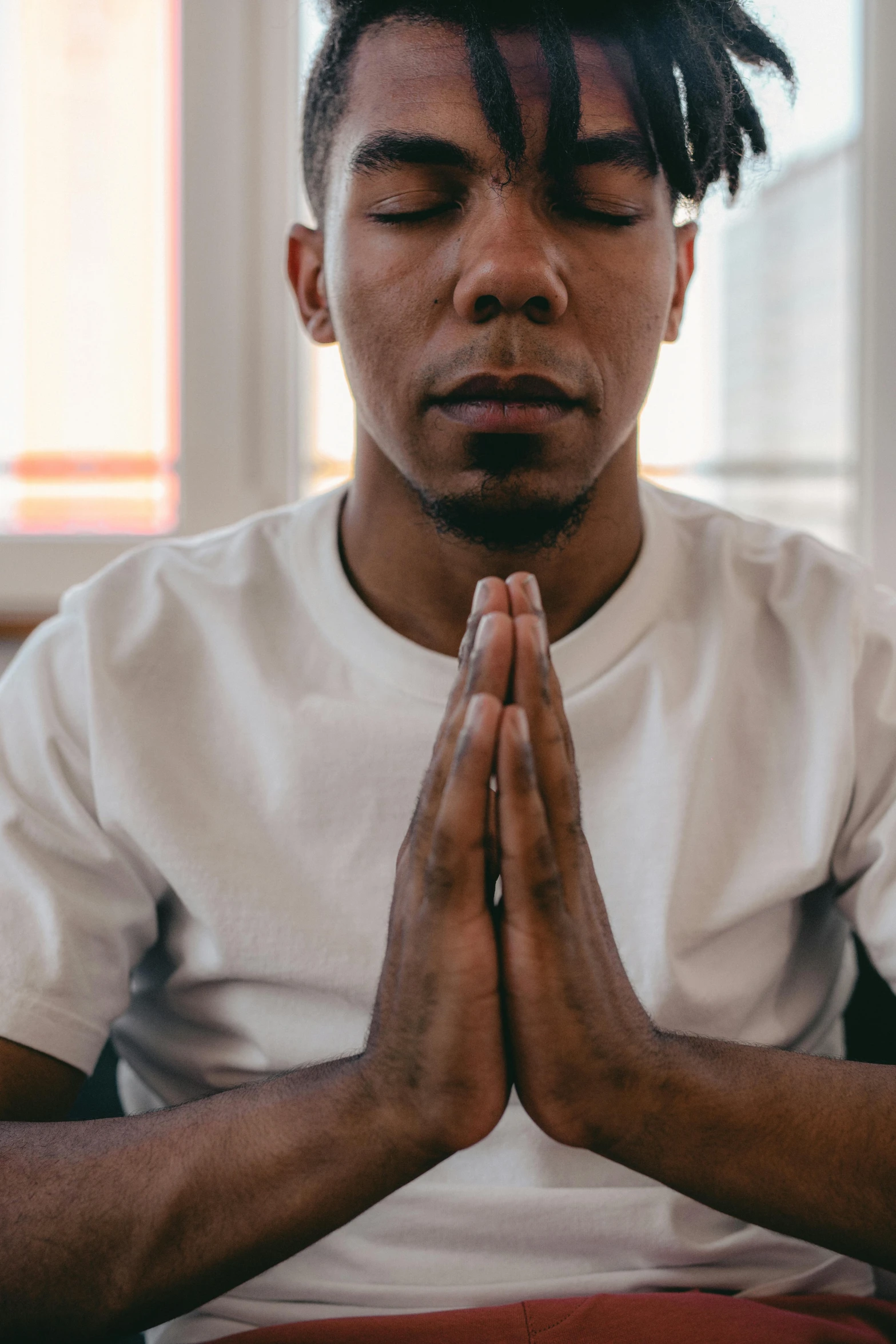 a man sitting in a prayer position with his hands together