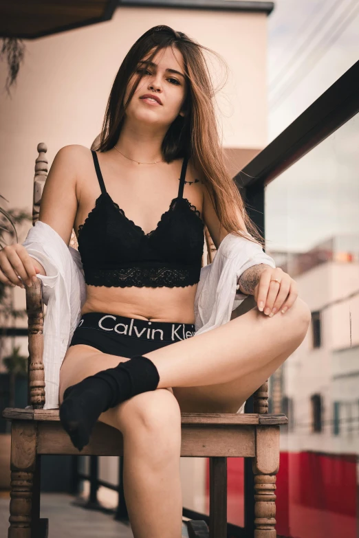 a young woman is sitting on a wooden chair with stockings