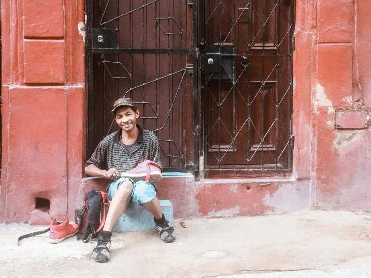 a man sits on the curb, with his luggage beside him