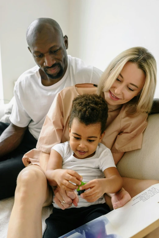 a woman is holding her little boy and he is sitting on the couch