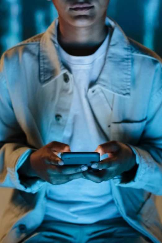 a man sits holding a smart phone in his hands