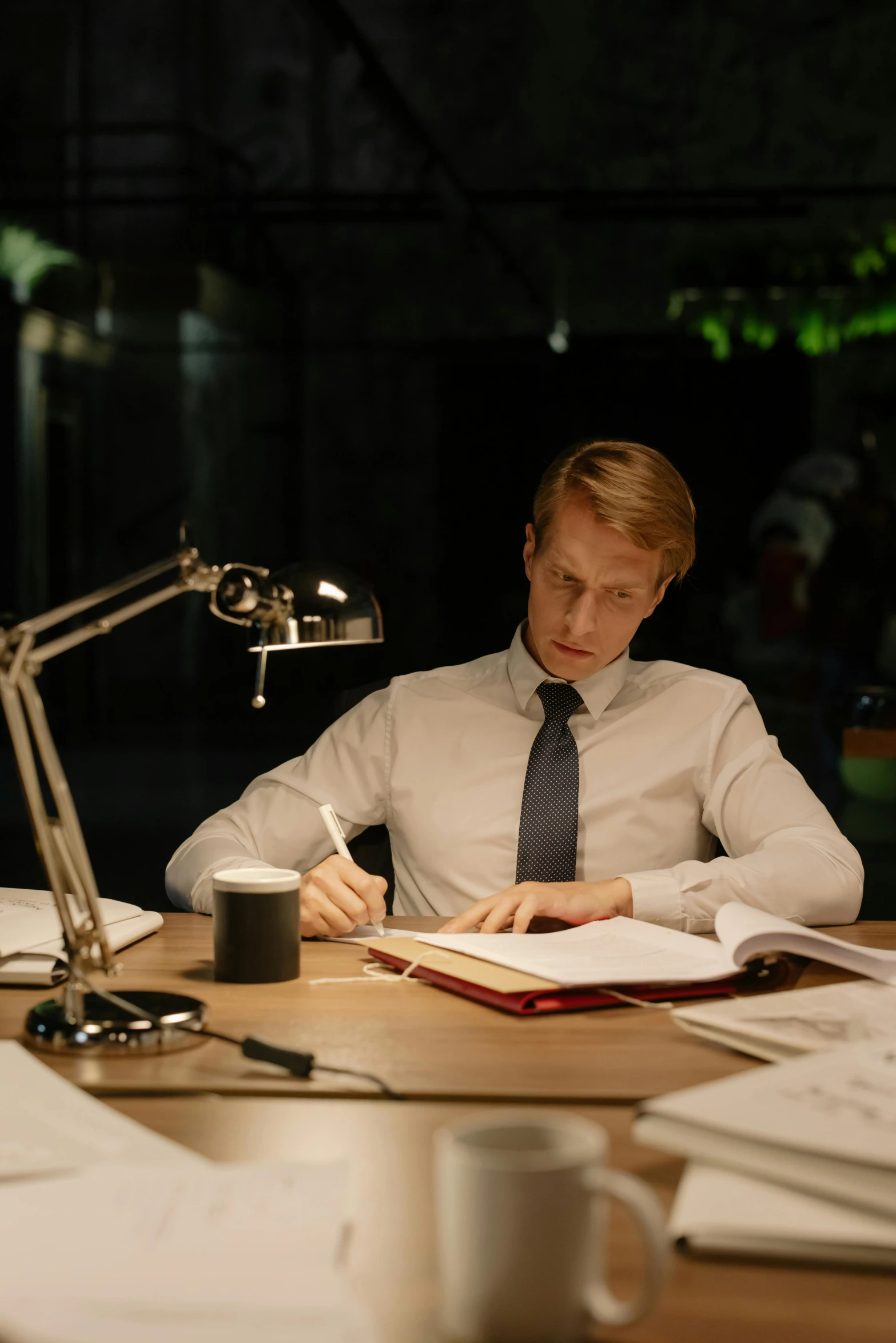 a man sitting at a desk with his book and a lamp on it