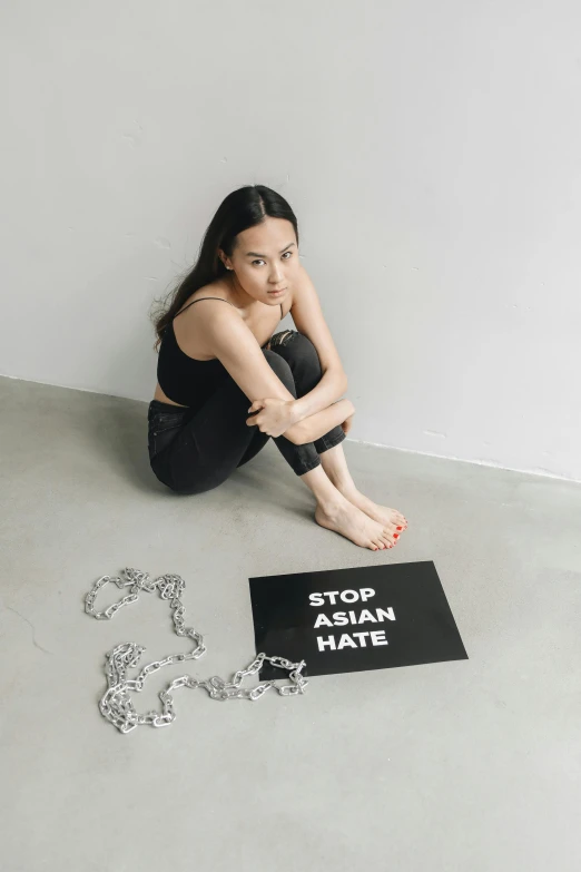 a young woman sitting on the ground wearing black and white