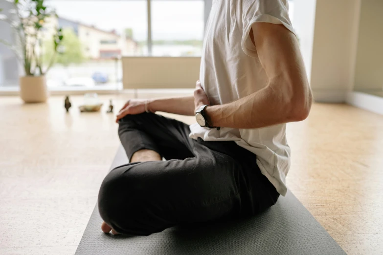 man sitting on yoga mat doing stretching exercises