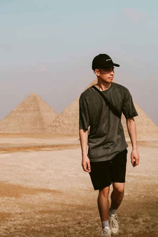 a young man is walking in front of pyramids