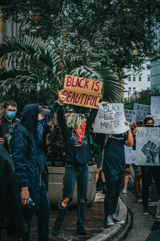 several people holding protest signs, one has a black is beautiful sign