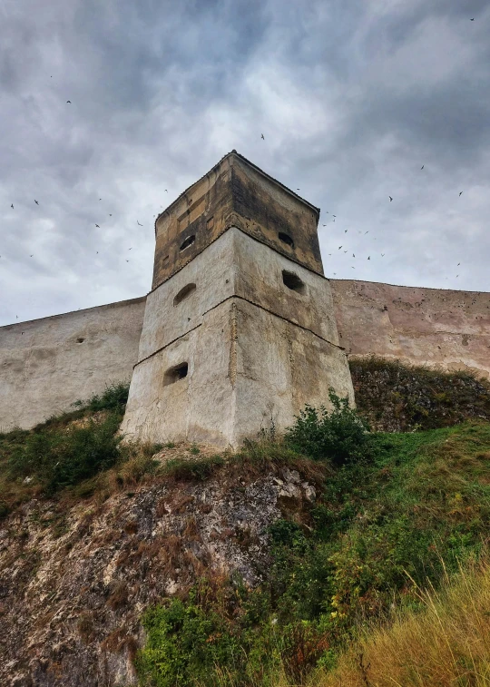 an old brick tower is standing on the side of a hill