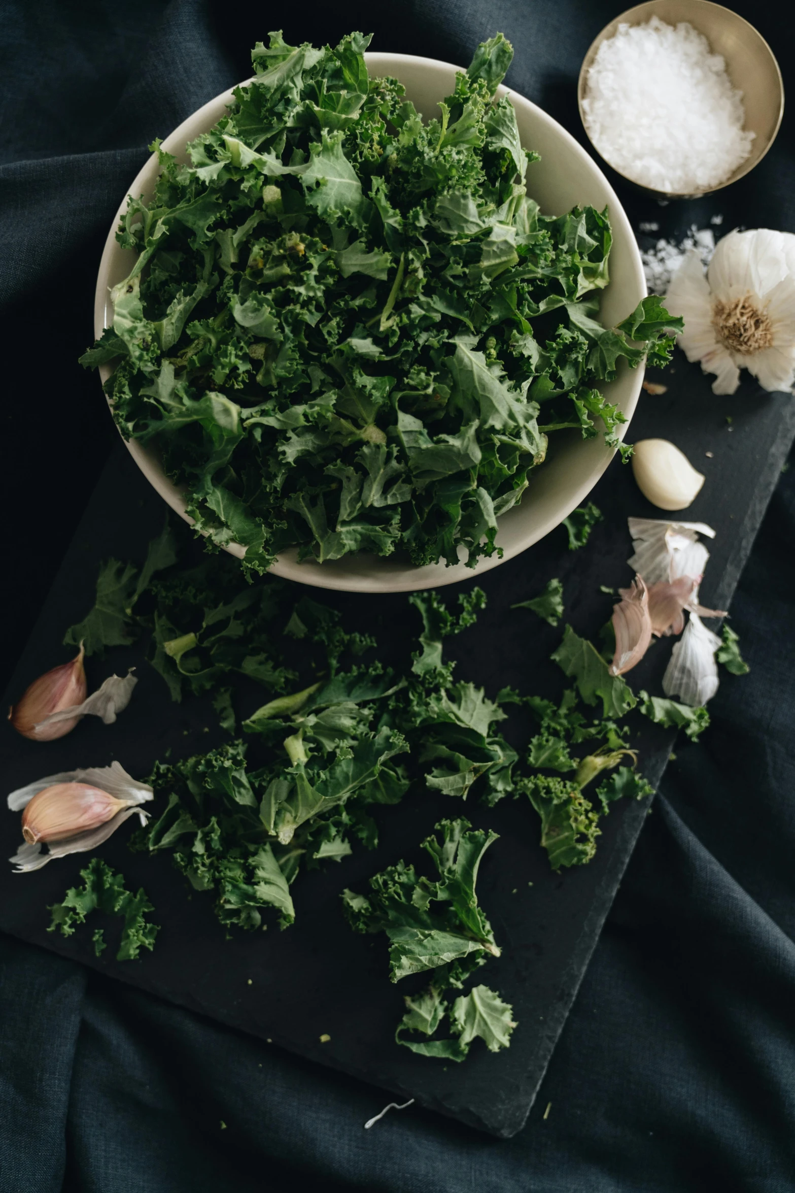 green vegetables are next to some garlic on a black table