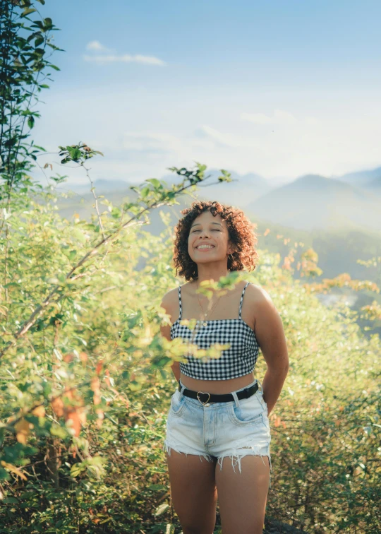 the woman smiles as she stands next to a bush