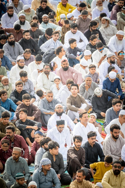 a crowd of men siting on their knees and pray