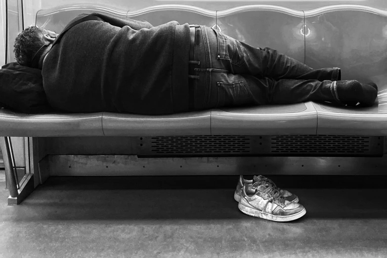 a person laying on a bench with sneakers nearby