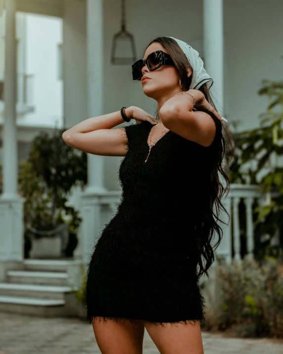 a beautiful woman standing wearing sunglasses on the street