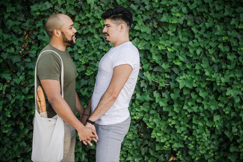 two males shaking hands standing near a very tall wall