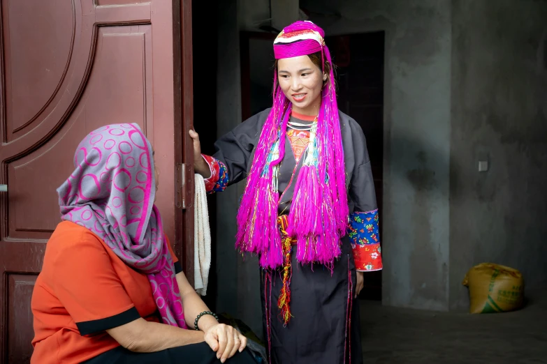 a girl with pink hair and a colorful scarf looks out of the doorway