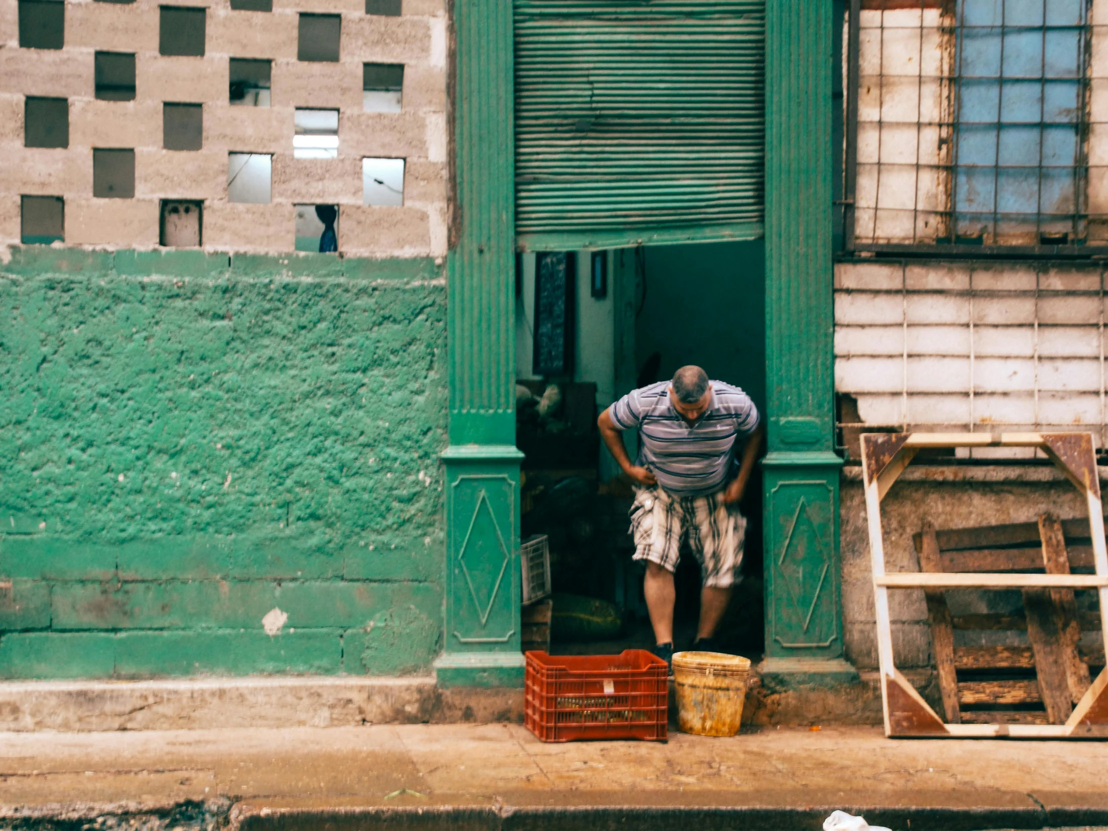 a man stands at a doorway in front of his dilapidated home