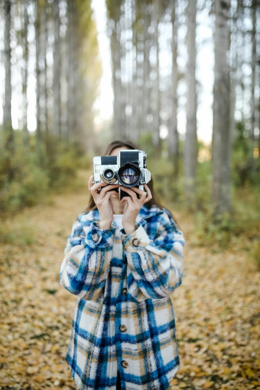 a person standing in a forest taking pictures with a camera