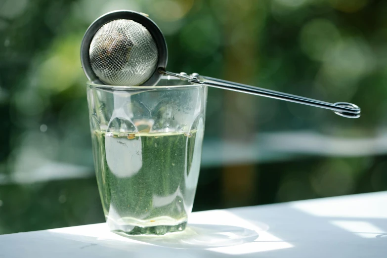 a glass with water and a metal strainer