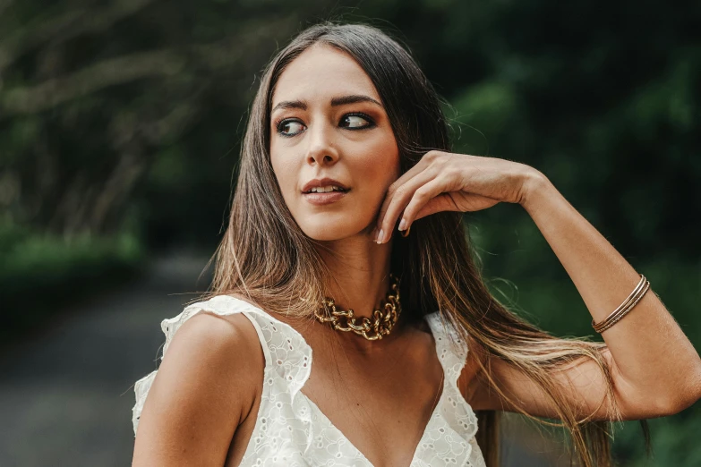 a woman wearing an elegant white dress with a gold statement necklace