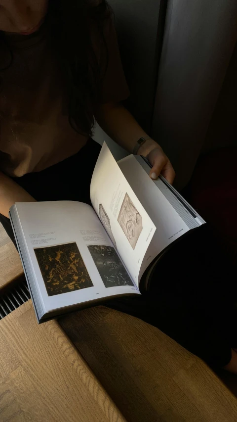 a woman is sitting on a chair holding an open book