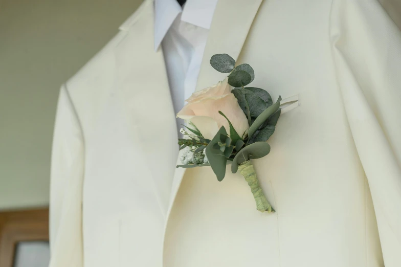 the man in a white suit is wearing a boutonniere