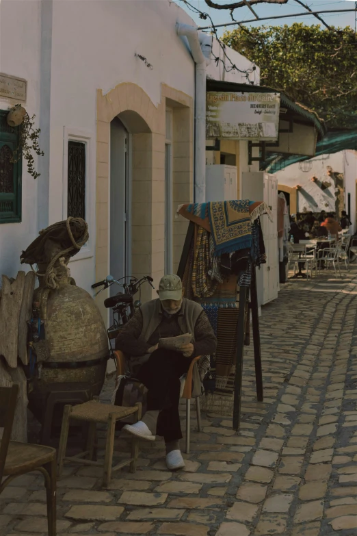 a person sitting on the street by some shops