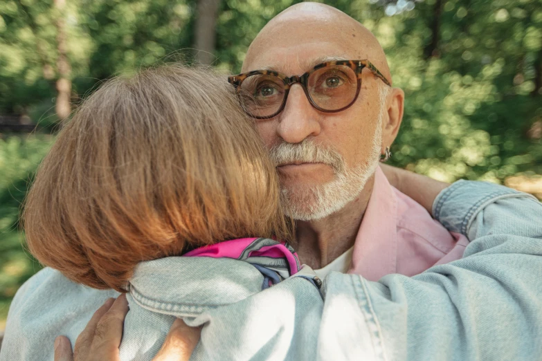 a man with glasses hugging a lady's shoulders