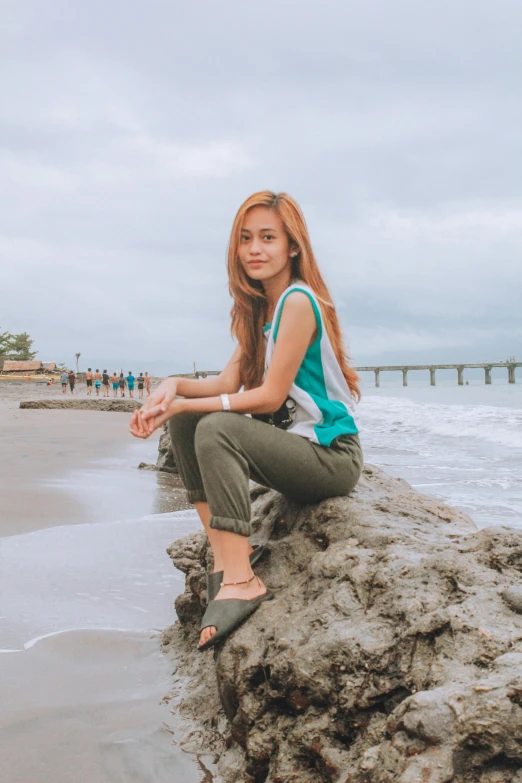 a woman is sitting on a rock by the ocean