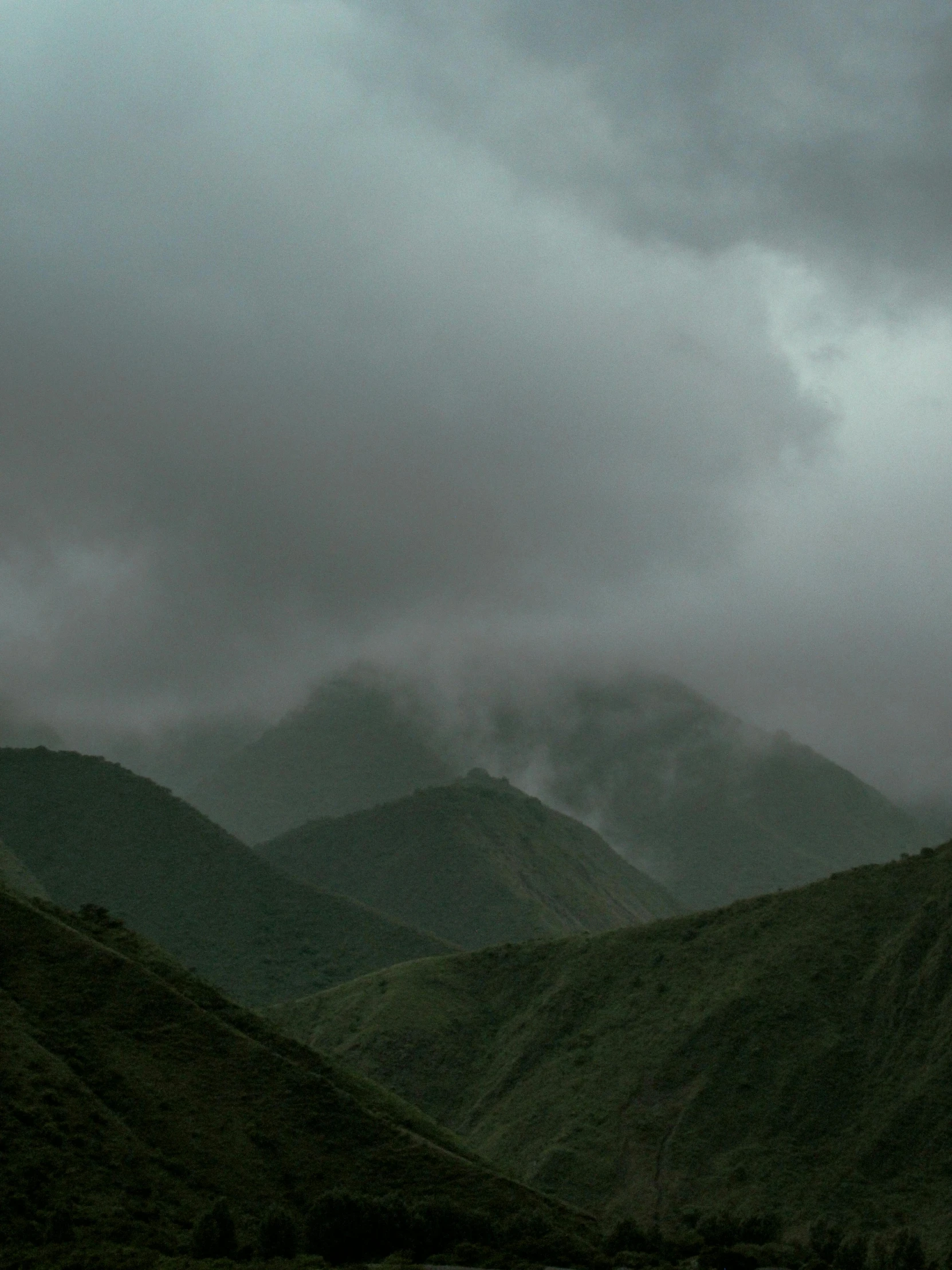 a few hills covered in clouds and trees