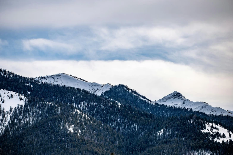 several snow covered mountains sitting under a cloudy sky