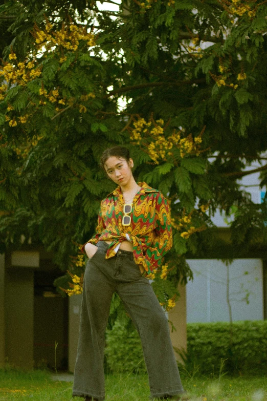 a woman poses for a pograph in front of some trees