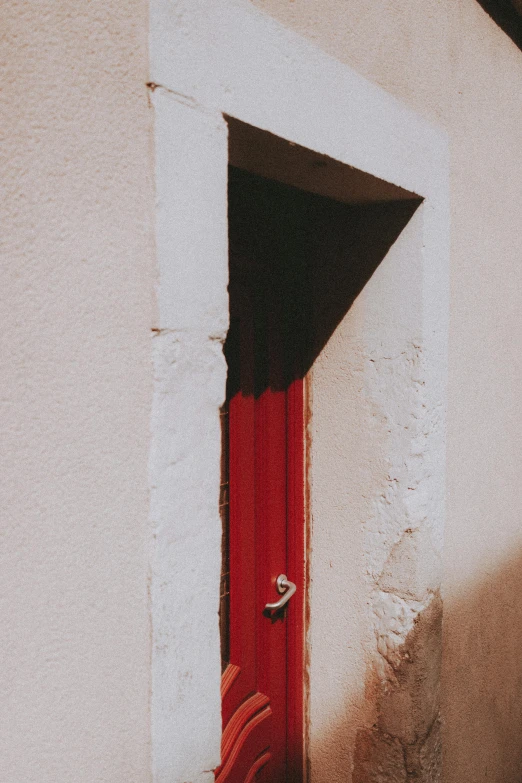 a red door in the corner of a white wall