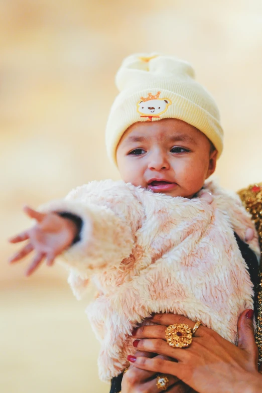 a baby girl dressed in a white fur jacket with her mom