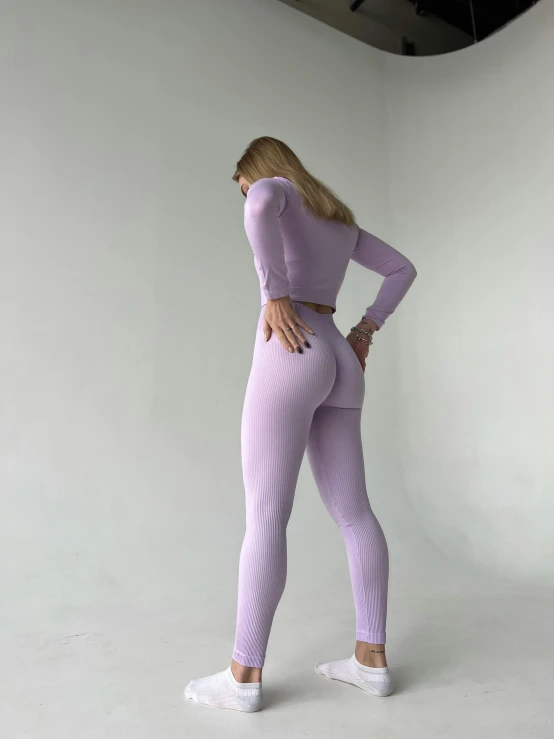 woman in lavender long - sleeve top and yoga pants leaning on one leg