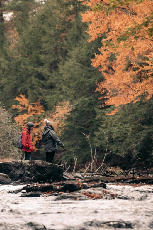 two people stand on the edge of a river while it flows through them